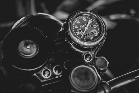 Velocimetro de uma motocicleta antiga com contador de 0 à 140 km por hora, imagem em preto e branco.